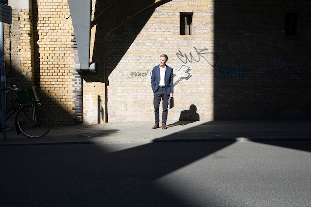 Biznesmen stojący na ścianie graffiti, rozglądający się