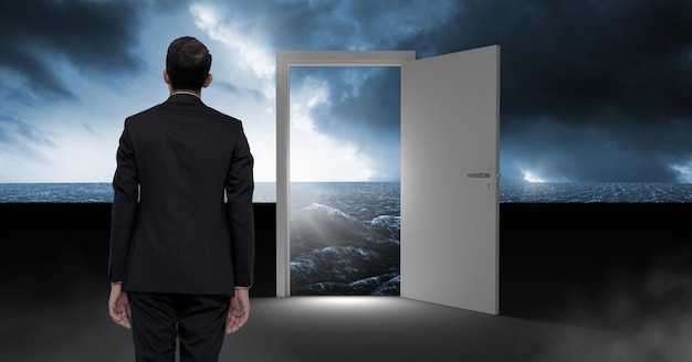 Biznesmen stojący przy otwartych drzwiach z surrealistycznym ciemnym blaskiem morza i niebem