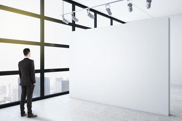 Biznesmen stojący w czystym wnętrzu galerii z miejscem na kopię na białej ścianie