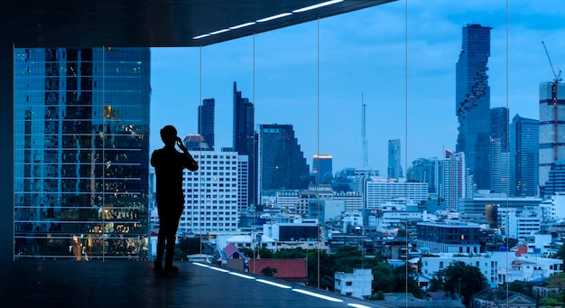 Biznesmen stojący za pomocą smartfona w nowoczesnej przestrzeni oglądając nocny widok miasta