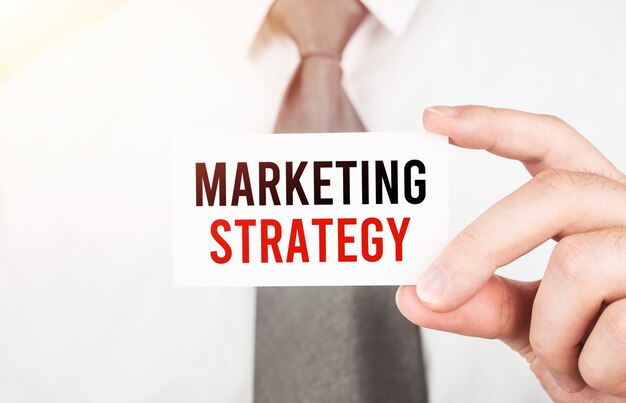 Biznesmen trzyma kartę z tekstem Strategia marketingowa, koncepcja biznesowa