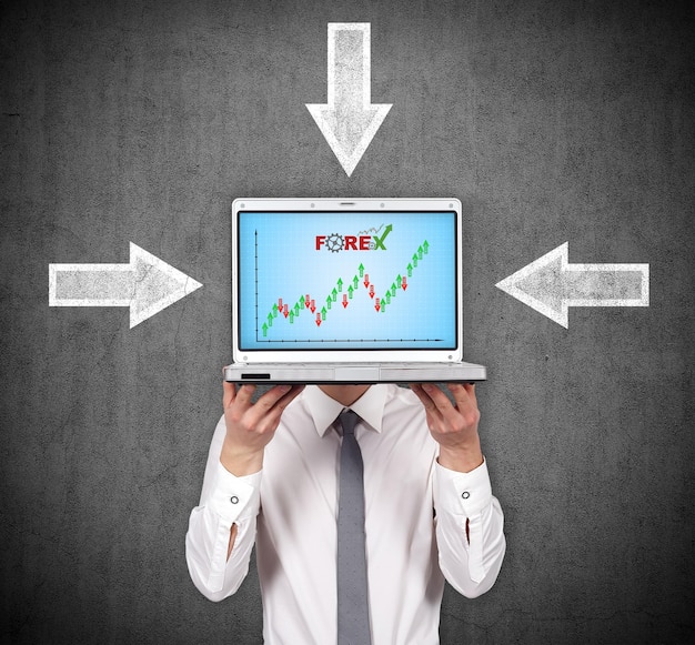 Biznesmen trzyma laptopa z wykresem giełdowym