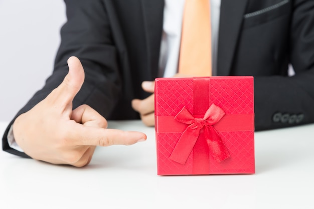 Zdjęcie biznesmen trzyma out prezent czerwieni pudełko, odosobniony tło