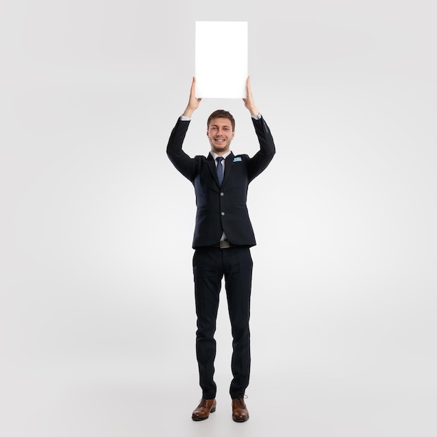 Biznesmen trzyma pustą białą tablicę reklamową w studio