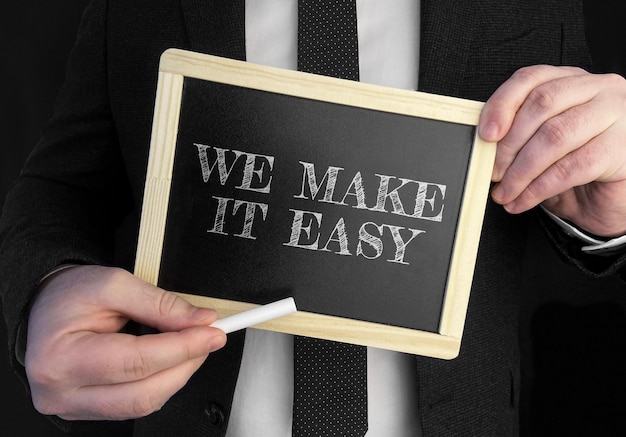 Zdjęcie biznesmen trzyma tablicę z tekstem we make it easy