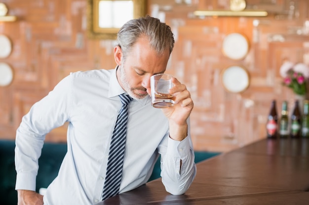 Zdjęcie biznesmen trzymając szklankę whisky na czole