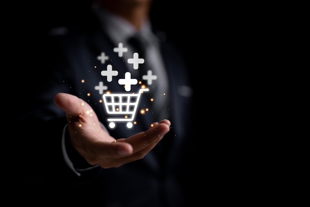Biznesmen trzymający ikonę wirtualnego koszyka na zakupy ze znakiem plus, aby dodać lub odebrać zamówienie, jest przedstawiony w tej opartej na technologii koncepcji firmy do zakupów online