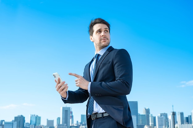Biznesmen trzymający smartfon i błękitne niebo