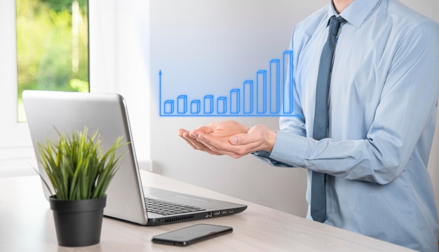 Zdjęcie biznesmen trzymający tablet i pokazujący holograficzne wykresy i statystyki giełdowe osiągania zysków koncepcja planowania wzrostu i strategii biznesowej wyświetlanie dobrej gospodarki z cyfrowego ekranu