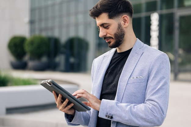 Biznesmen trzymający tablet w rękach przy użyciu aplikacji biznesowych na komputerze typu tablet szczęśliwa twarz wyglądający tablet