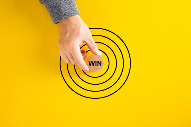 Zdjęcie biznesmen umieścił okrągły blok ze słowem „wygraj”, dążąc do koncentrycznych kręgów celu marketingowego