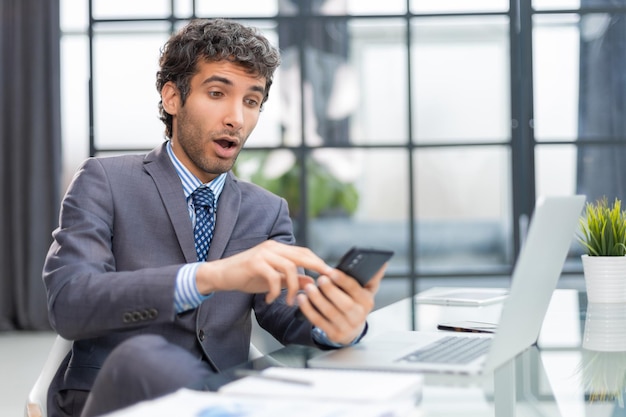 Biznesmen używa jego telefon komórkowego w biurze