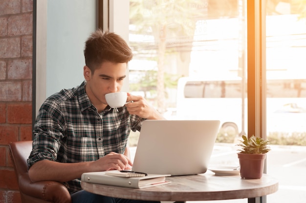 Biznesmen używa laptop w sklep z kawą z filiżanką latte