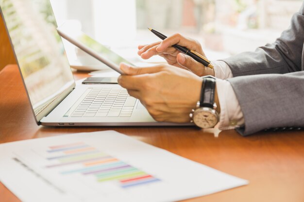 Biznesmen używa pastylkę i laptop pracuje na pieniężnym planie