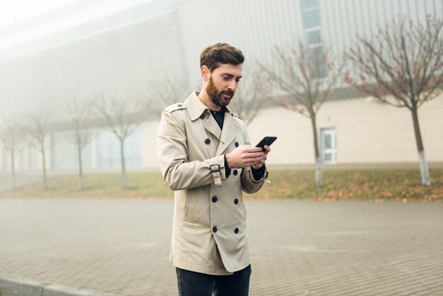 Biznesmen używa smartphone podczas gdy chodzący