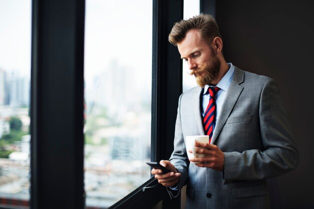 Biznesmen używający telefonu i pijący kawę