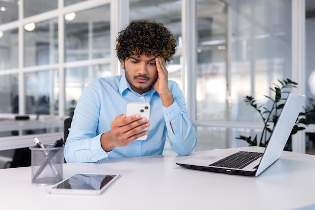 Biznesmen w biurze w miejscu pracy nie jest zadowolony z pracy telefonu mężczyzny