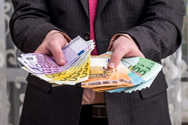 Biznesmen w garniturze pokazano zarobki, banknoty euro