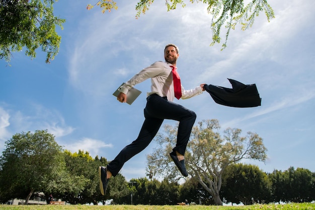 Biznesmen w garniturze skaczący przez park miejski Portret odnoszącego sukcesy biznesmena Szybka koncepcja biznesowa