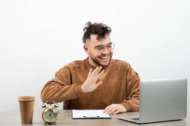 Biznesmen w okularach siedzi i ma rozmowę służbową na laptopie.