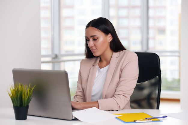 Biznesmen w różowej kurtce siedzi na laptopie w biurze