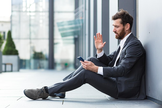 Biznesmen w rozpaczy donosi złe wieści rozmawiając przez telefon, przygnębiony i smutny, siedzący w biurze stracił nadzieję