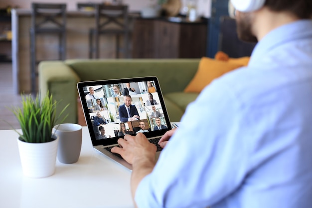 Biznesmen w słuchawkach mówi, rozmawiaj podczas rozmowy wideo z kolegami na briefingu online