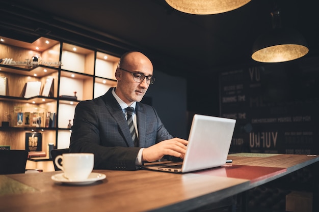 Biznesmen w średnim wieku w biznesie i okulary pracy za pomocą laptopa