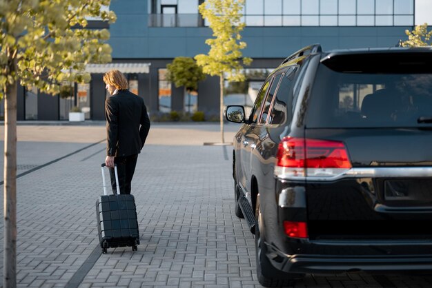 Zdjęcie biznesmen wchodzi z walizką do biurowca lub samochodu hotelowego z przodu koncepcja transportu i podróży służbowych