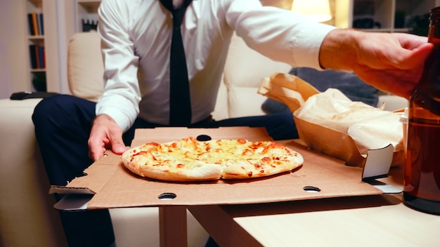 Biznesmen wraca do domu z pizzą po długim dniu w pracy. Odpoczynek po pracy.