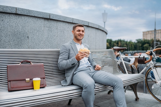 Biznesmen z cyklu je obiad na ławce w biurowcu w centrum miasta.