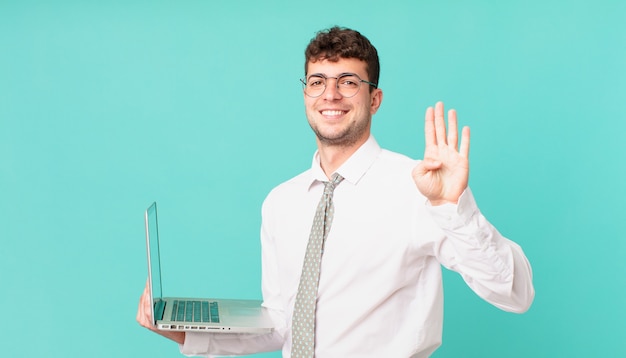Biznesmen Z Laptopem Uśmiecha Się I Wygląda Przyjaźnie, Pokazując Cyfrę Cztery Lub Czwartą Z Ręką Do Przodu, Odliczając W Dół