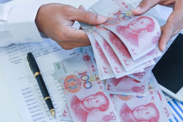Biznesmen z pieniędzmi w ręku, Yuan, inwestycje, sukces i zyskowne koncepcje biznesowe.