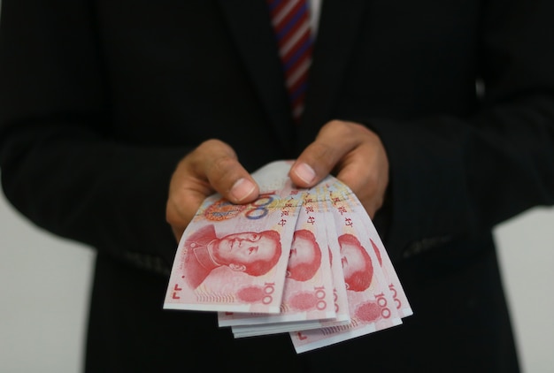 Biznesmen z pieniędzmi w ręku, Yuan, inwestycje, sukces i zyskowne koncepcje biznesowe.