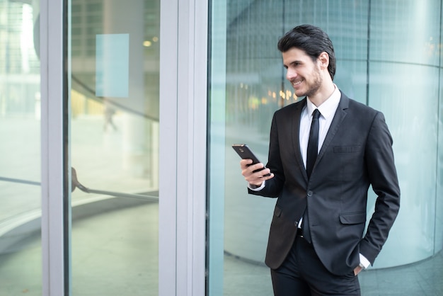 Biznesmen za pomocą aplikacji na swoim smartfonie w środowisku biznesowym