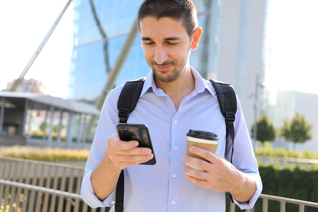 Biznesmen za pomocą telefonu komórkowego i picia kawy w mieście