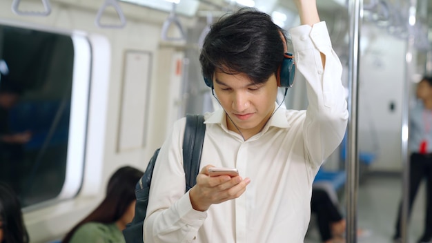 Biznesmen za pomocą telefonu komórkowego w pociągu. Koncepcja dojazdów do pracy miejskiego stylu życia.