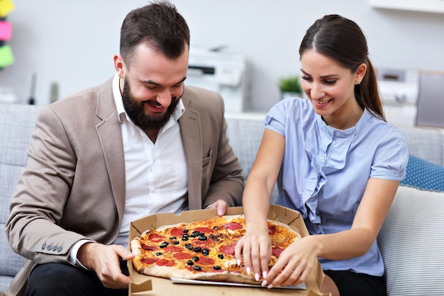 biznesmeni jedzący pizzę w biurze