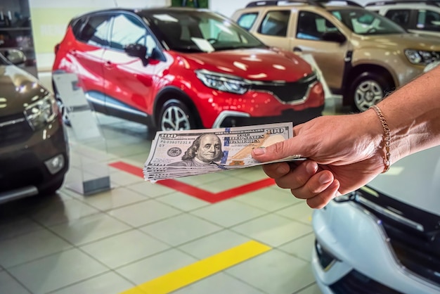 Biznesmenka w salonie samochodowym otrzymała dużą sumę banknotów dolarowych za nowy samochód. Pojęcie kupna samochodu. Koncepcja wnętrza samochodu.