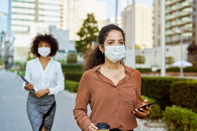 Biznesmenki spacerujące po mieście w maskach ochronnych