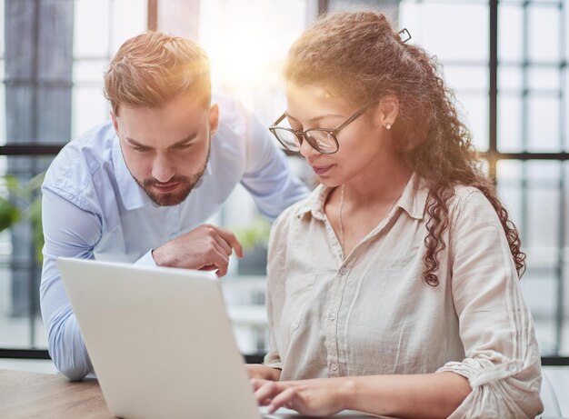 Biznesowa dama patrzy na laptopa z kolegą w biurze