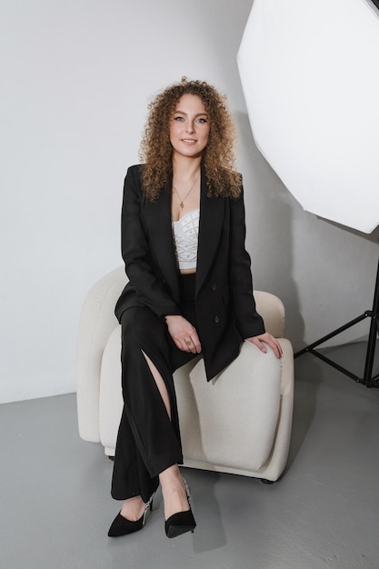 Biznesowa dziewczyna siedzi na białym krześle w studio