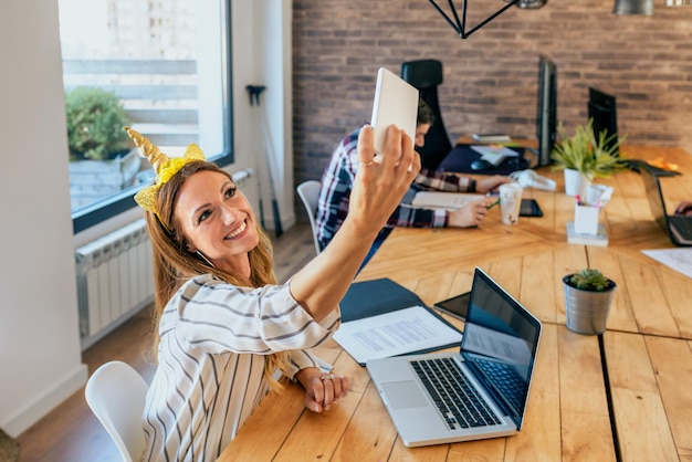 Zdjęcie biznesowa kobieta bierze selfie z jednorożcową opaską