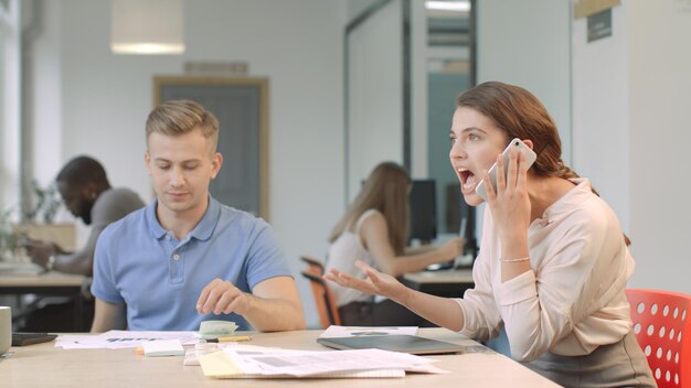 Biznesowa kobieta opowiada agresywnie na telefonie komórkowym Nerwowa kobieta ma rozmowę telefonicza