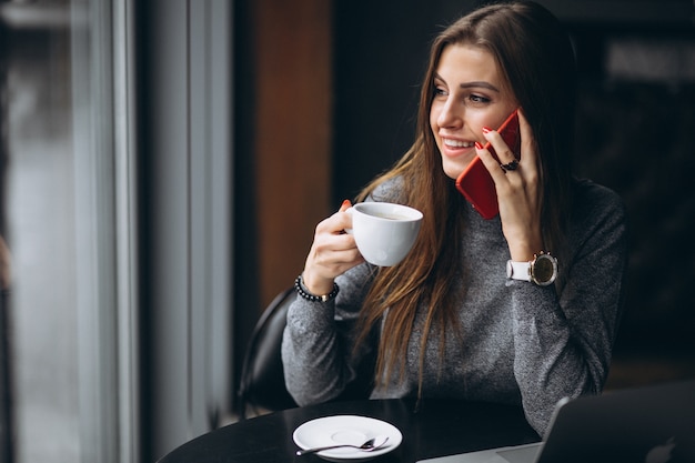 Biznesowa kobieta opowiada na telefonie i pije kawę w kawiarni