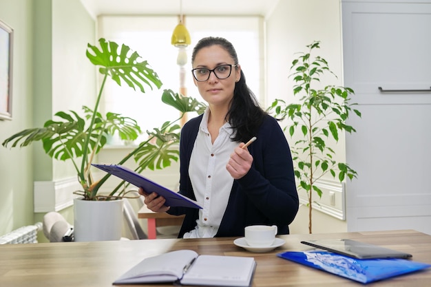 Biznesowa kobieta patrząca na kamerę rozmawiająca trzymająca dokumenty w rękach