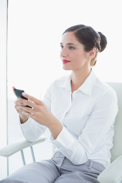Biznesowa kobieta patrzeje daleko od z telefonem komórkowym