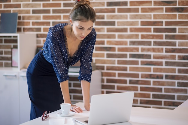 Biznesowa kobieta patrzeje laptop w biurze