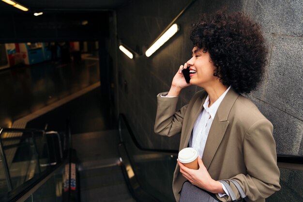 Biznesowa kobieta rozmawia przez telefon na schodach ruchomych