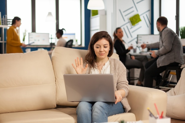 Biznesowa kobieta rozmawiająca podczas wideokonferencji z laptopa siedzącego na kanapie